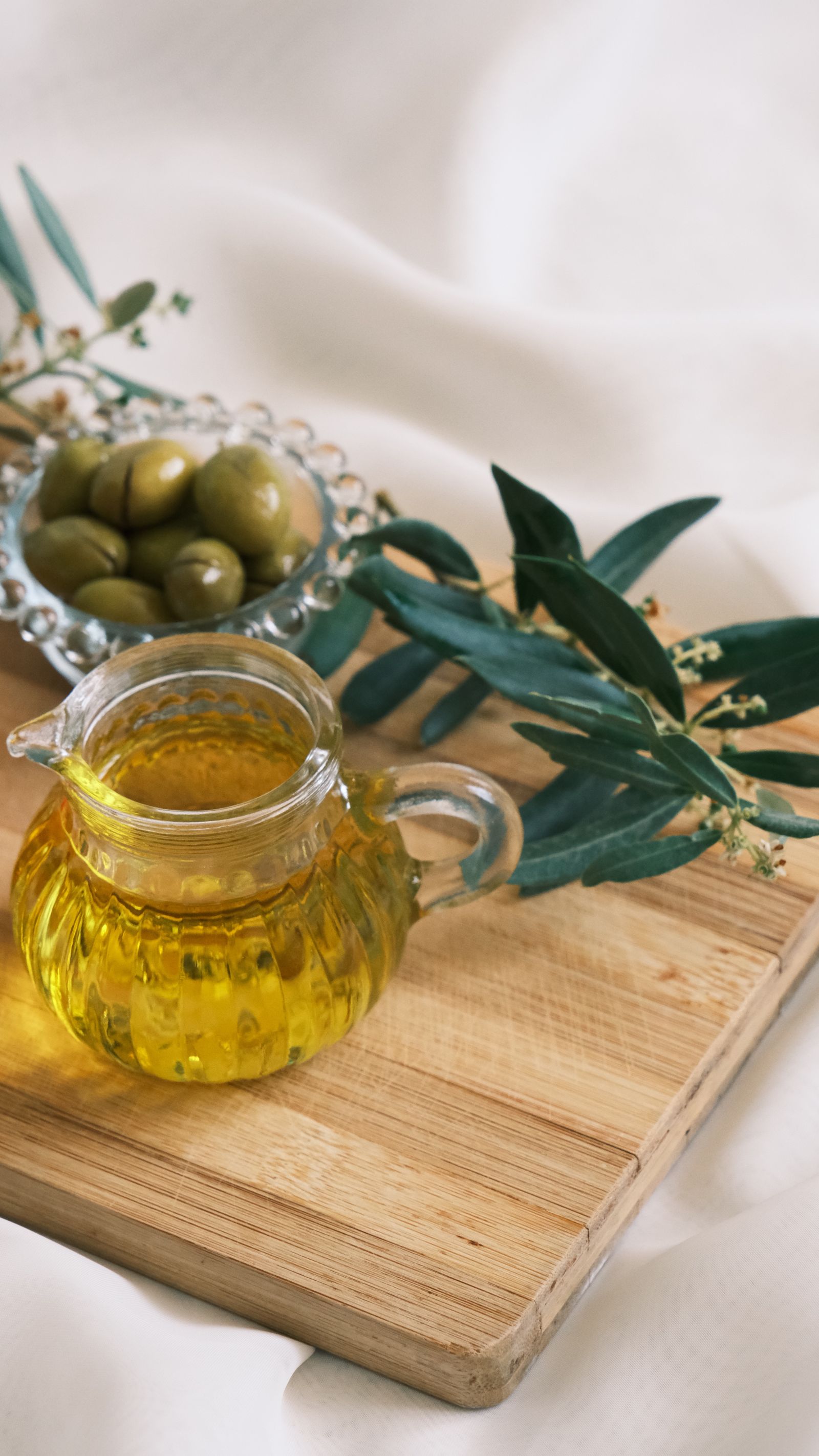 Olives, huile d'olive et branche d'olivier sur une planche